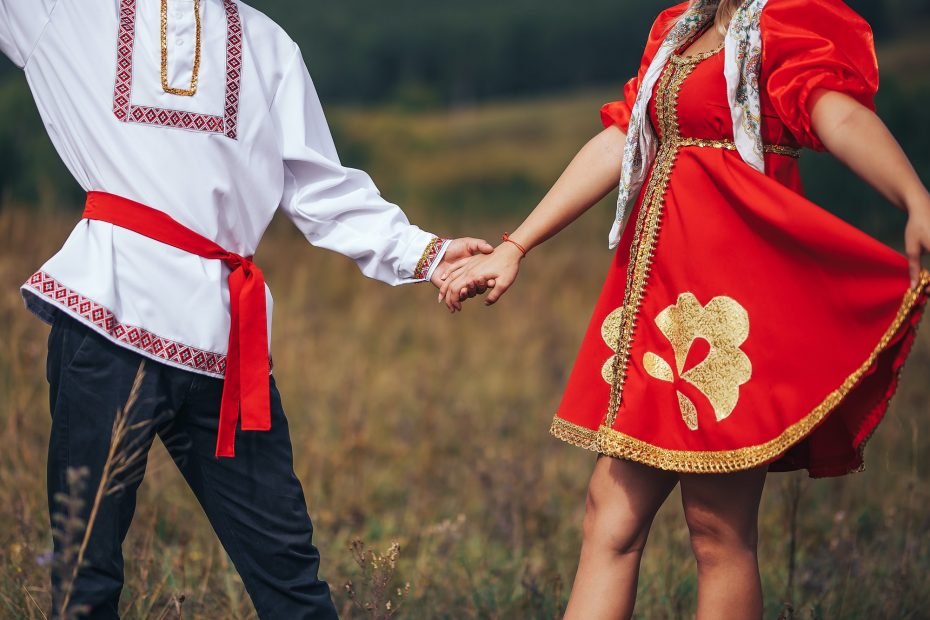Dancing guy and girl dressed in national Russian clothes are holding hands Art grain and noise on